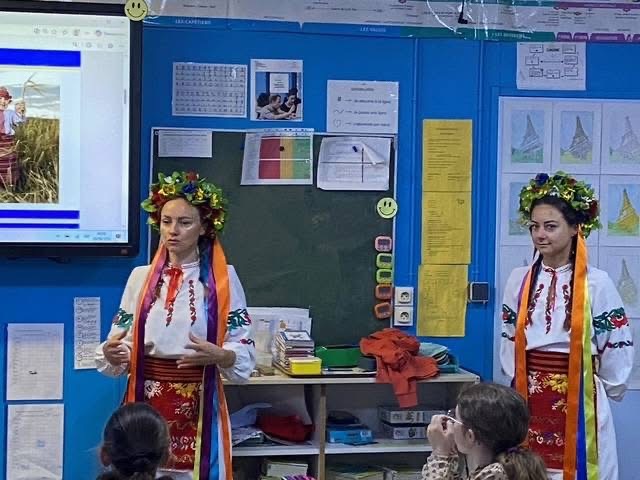 Deux jeunes femmes en costume traditionnel ukrainien présentent leur pays à une classe d’élèves