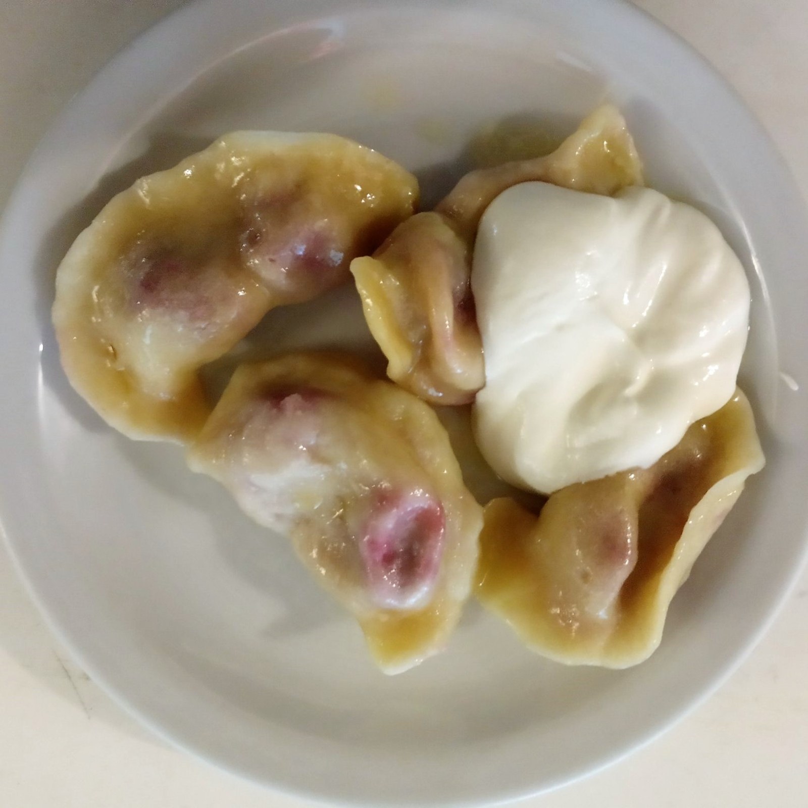Une assiette de varenyky aux cerises accompagnés de crème